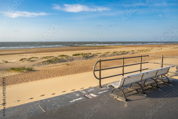 Fototapeta Park bench on the shore of North Sea. Wind makes structures in the sand at the ocean, natural art on the sandy beach, place to recreation on holiday