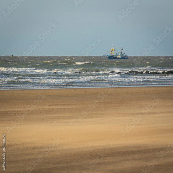Fototapeta single ship is sailing on the North Sea, ship, sails and waves shine in the evening light, North Sea beach before sunset with waves of the ocean
