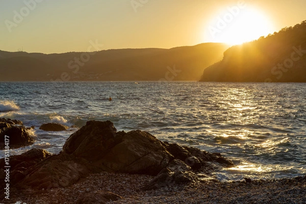 Obraz Sunset on a Mediterranean beach. The cliffs and sea are painted with orange sunlight.