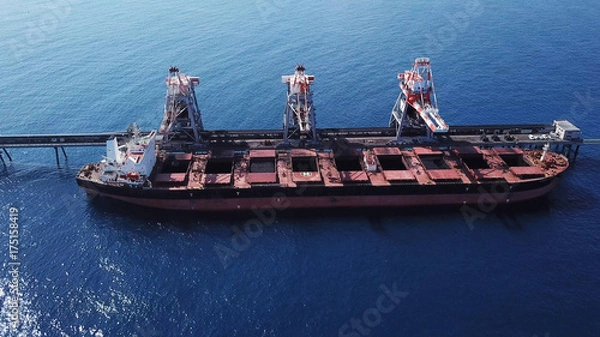 Obraz Large bulk carrier ship docking - Unloading coal ship by cranes on the power station dock