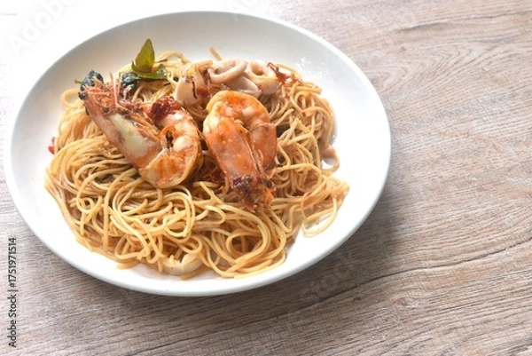 Obraz spicy fried vegetarian Chinese yellow rice noodles with shrimp and squid couple chili basil on plate