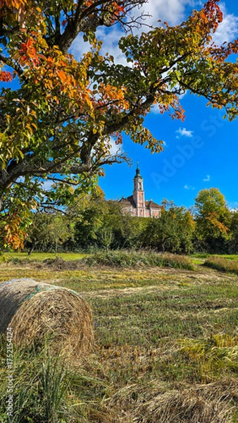 Obraz View of the Pilgrimage church Birnau in autumn day. Straw bale and tree with yellow red leaves in the foreground. Lake Constance, Baden-Wurttemberg, Germany.
