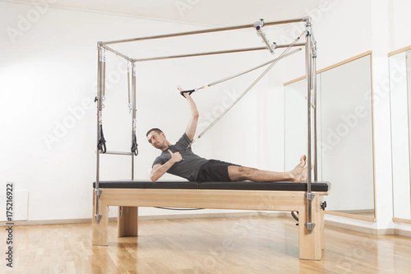 Fototapeta Pilates instructor performing exercise on cadillac equipment