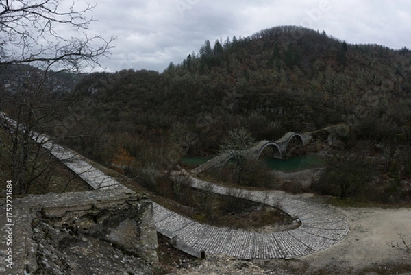 Fototapeta View of the traditional stone Kalogeriko or Plakidas bridge with cobblestone path on a winter day, Zagori, Epirus, Greece