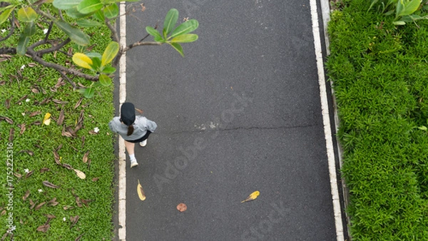 Obraz Woman walking on a path in a park, overhead view