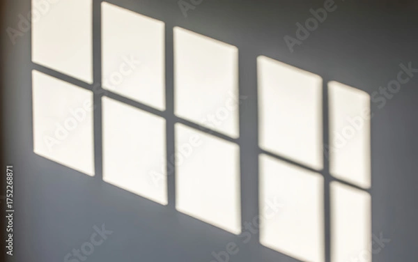 Fototapeta Sunlight casting geometric shadow patterns on a wall