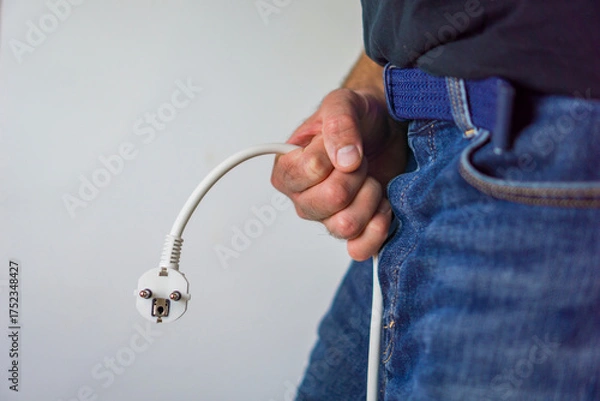 Fototapeta Male impotence and erectile dysfunction, showing a man holding a power plug to represent loss of energy and vitality.