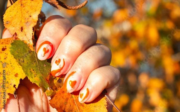 Fototapeta female hands with orange beautiful manicure on the background of autumn leaves