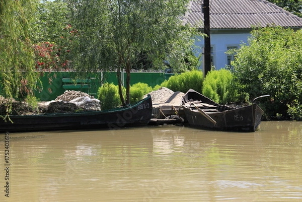 Fototapeta rustic waterfront scene where weathered black boats 