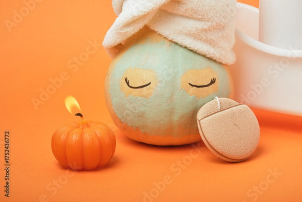 Fototapeta Pumpkins and bottles of cosmetic products on bright orange background, candles and reusable pad, autumn self care