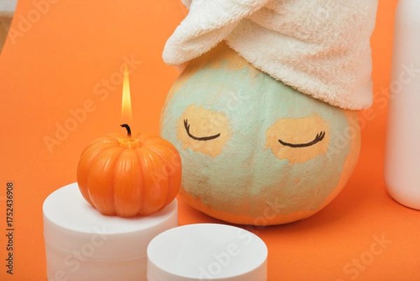 Fototapeta Mock-up jars of cream and yellow pumpkin in a clay mask and a towel on the head Natural organic spa cosmetics concept. Vitamin intense seed of pumpkin cream concept.