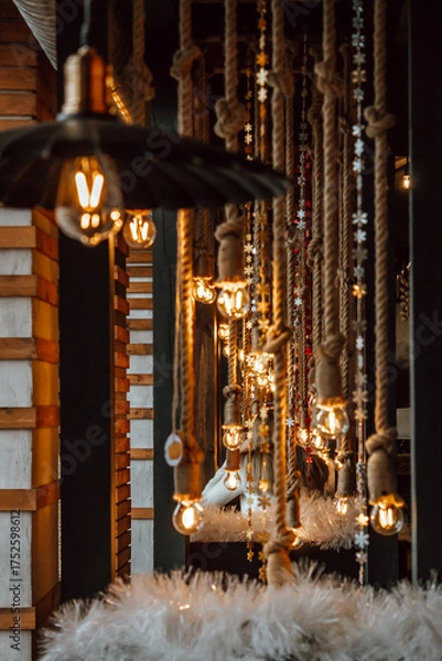Fototapeta indoor area features hanging lights and ropes, creating warm and inviting festive atmosphere. soft lighting enhances rustic decor, perfect for late-night gatherings christmas. vertical. close up.