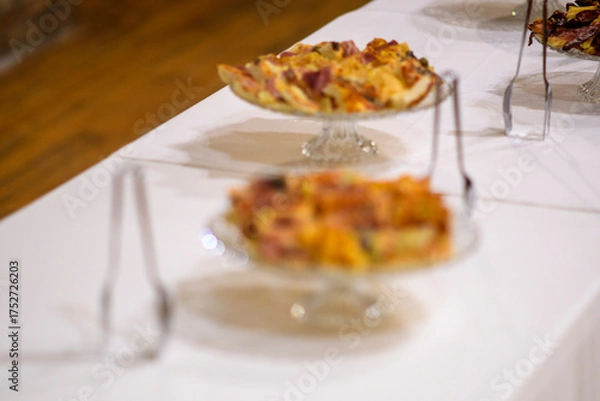 Fototapeta Deliciously prepared savory pies and tarts artfully arranged on a white tablecloth for a catered event or celebration with a focus on exquisite culinary presentation