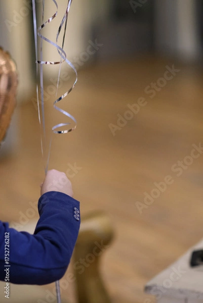 Fototapeta A jubilant young girl raises her fist in a gesture of triumph and celebration surrounded by festive streamers 