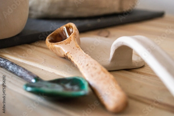 Fototapeta in neat workspace, handcrafted ceramic spoon rests beside clay tools on wooden table. soft natural light highlights textures and details crafts. close up.