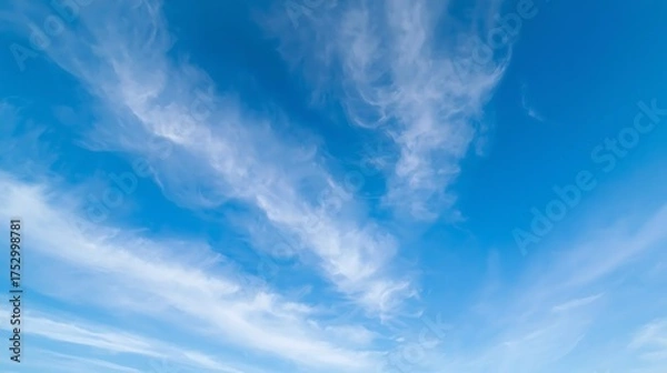 Obraz Wispy cirrus clouds drift across a vast expanse of bright blue sky on a clear day