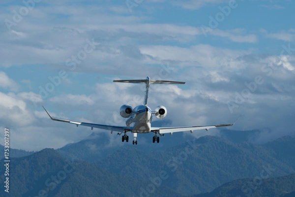 Obraz Landing of a private plane at Batumi Airport against a backdrop of mountains and a cloudy sky.