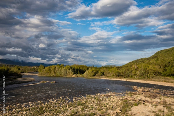 Obraz Serene river landscape with dramatic cloudscape, perfect for travel blogs or nature documentaries, showcasing the beauty of the great outdoors and calming waters