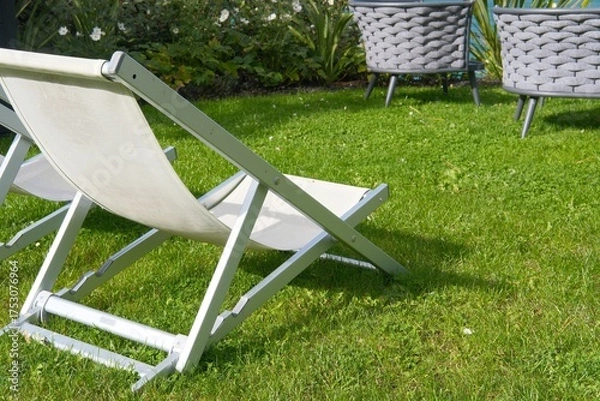 Obraz Empty lawn deck chair on grass lawn or park, relaxation on summer or spring sunny day. Hotel space, traveling and vacations on resorts. Garden furniture