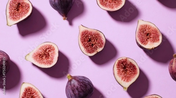 Fototapeta Whole and halved figs lie in a flat lay on pastel purple, revealing detailed seeds, soft shadows, and rich color in a clean minimal composition suited for food, nutrition, freshness concepts.