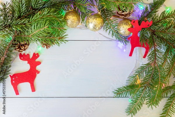 Fototapeta A New Year's composition with spruce branches, cones, golden balls, red figures of deer and a garland