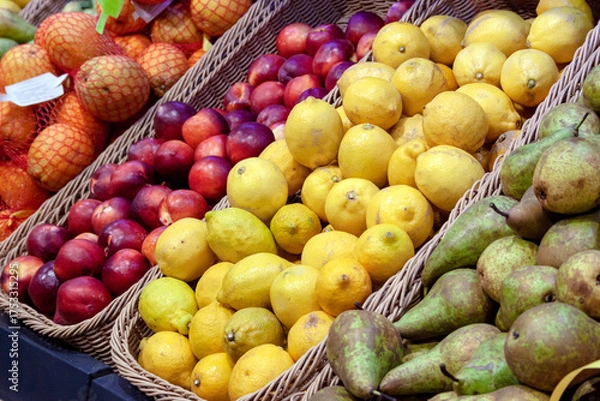 Fototapeta Lemons and nectarines lie in baskets on the counter, standing out with rich colors.