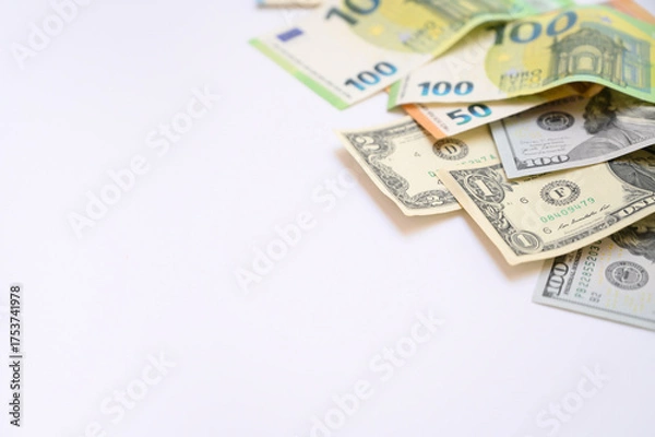 Fototapeta Euro and US dollar banknotes scattered on a white background with copy space. Concept of international finance, currency exchange, business, and global economy suitable for commercial design projects.
