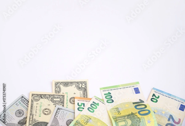 Fototapeta Euro and US dollar banknotes scattered on a white background with copy space. Concept of international finance, currency exchange, business, and global economy suitable for commercial design projects.