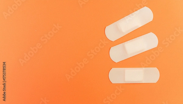 Fototapeta Adhesive bandages on orange background symbolizing healing and care