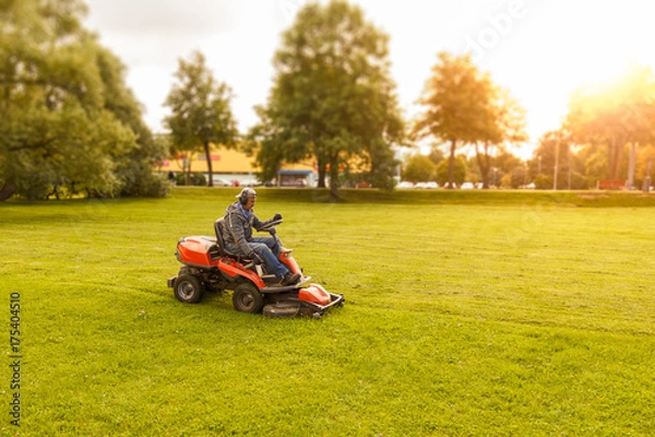 Fototapeta traktor kosiarka pracuje w parku miejskim