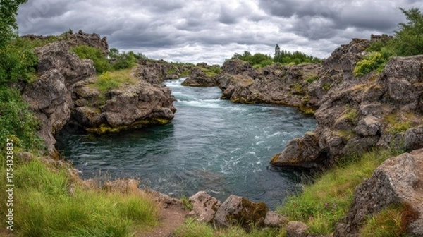 Obraz River flows through rocky landscape under dramatic cloudy sky