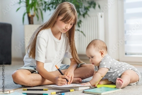 Obraz Older sister drawing with baby at home on floor. Early development