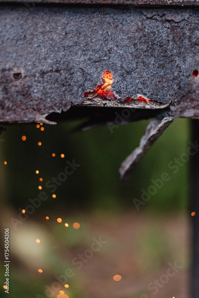 Fototapeta Sparks are flying out of an old, rusty, burnt-out metal grill - the damaged grill needs to be updated