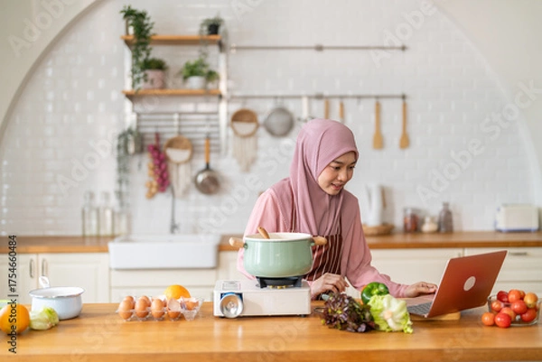 Fototapeta Muslim woman vlogger live streaming cooking online in kitchen look at camera with vegetables, content creator culinary class at home studio, halal food influencer cooking live, video for social media