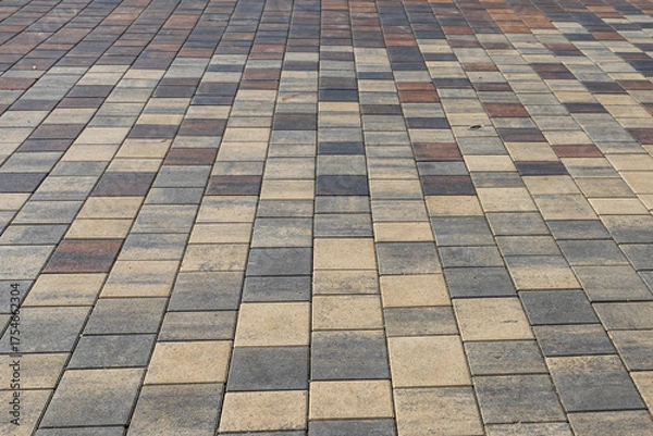 Obraz Paving slabs for paths. Paving slabs made of cement mix. Paving stones made of artificial materials. Laying tiles on the road. Material for covering sidewalks and streets. Repair of sidewalks