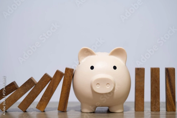 Obraz Piggy bank stopping falling dominoes symbolizes financial protection, risk management, savings stability, smart money planning ideal for content about personal finance and financial crisis prevention.