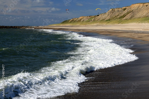 Fototapeta Landscape photo with a view of the North Sea coast, beach and paragliders in the background against a blue sky with clouds near Bovbjerg Lighthouse in Lemvig, Denmark