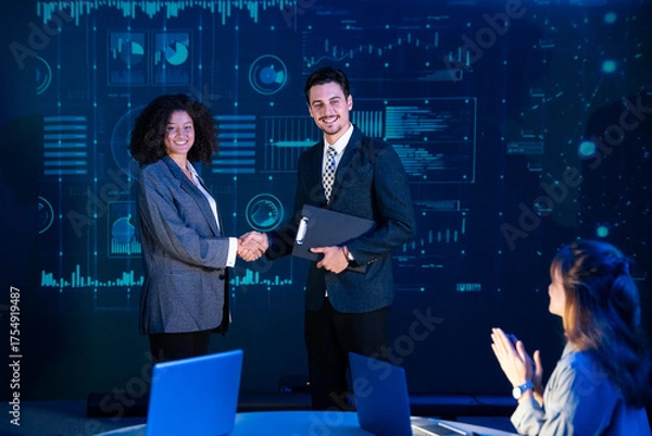Fototapeta Business professionals finalizing a deal or contract agreement, shaking hands in front of a data analysis screen.