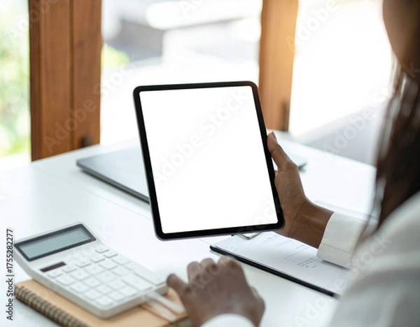 Obraz Businesswoman at office desk holding a tablet with a blank white screen mockup for app or website display