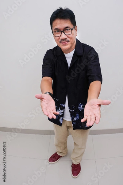 Fototapeta Man standing with both arms open gesturing warm welcome