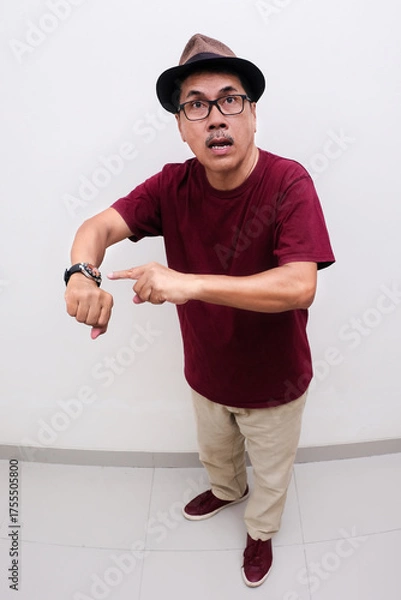Fototapeta Closeup shot of a man looking impatient by pointing finger at the wrist watch