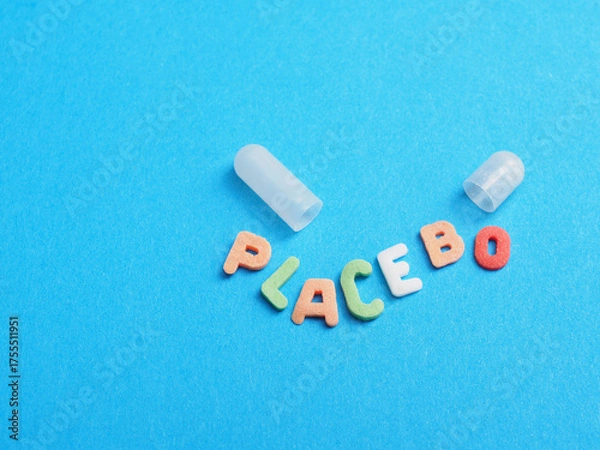 Fototapeta An open medicine capsule with the word “placebo” written in sugar letters. Medical or health care concept on a blue background
