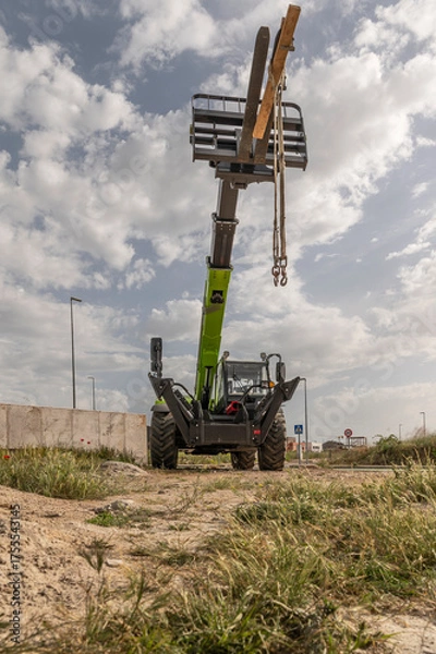 Fototapeta Forklift on a construction site, preparing to raise construction parts