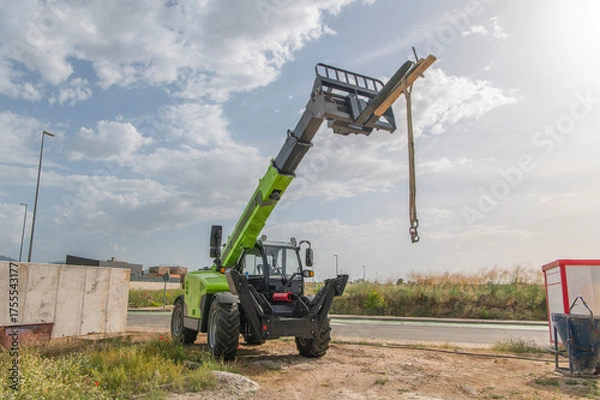 Fototapeta Forklift on a construction site, preparing to raise construction parts