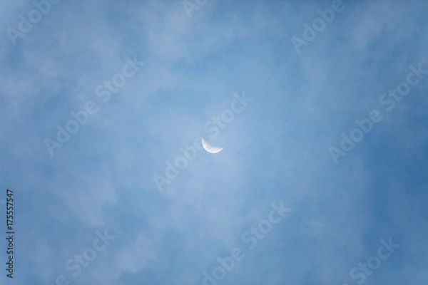 Obraz Small moon in the center photo with blue sky and behind little clouds.
