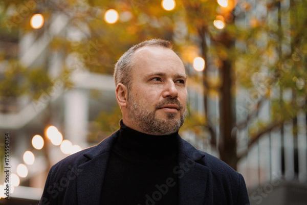 Obraz Portrait of elegant man in coat looking away on city street in autumn