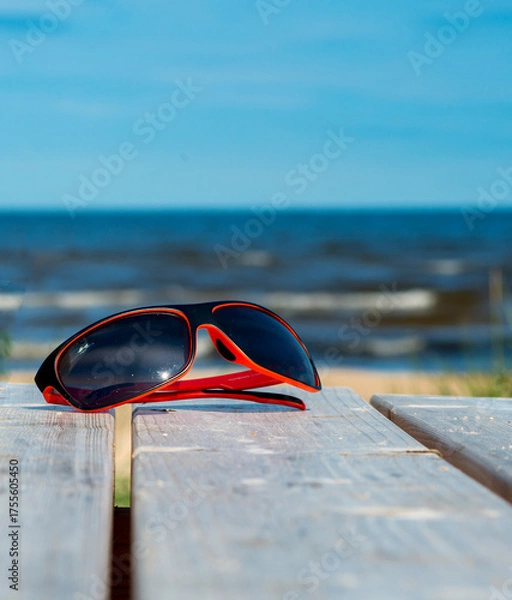 Fototapeta Sunglasses on wooden resting table on sandy beach of Jurmala - famous Baltic tourist  resort in Latvia, Europe. Sand beaches cover more than 26 km of coastline