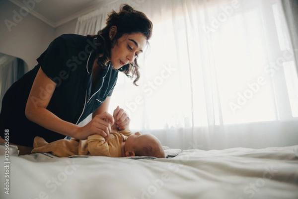 Obraz Mother lovingly interacts with baby son on bed by window