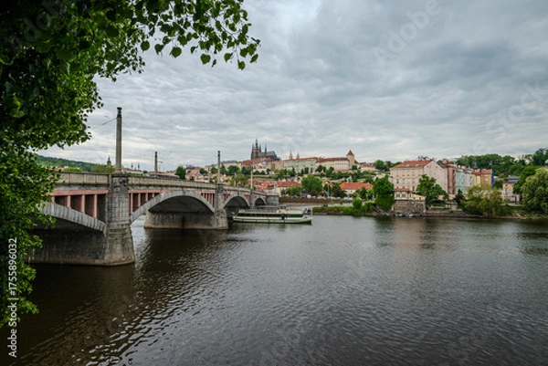 Fototapeta Manes Bridge over the Vltava River in Prague, Czech Republic, under soft May clouds, with a distant view of Prague Castle