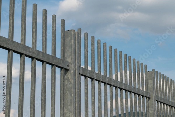 Fototapeta Building fencing made of galvanized steel, an ideal solution for outdoor security and protection. Sturdy and durable, it's perfect for garden and residential boundaries. Fence, street furniture